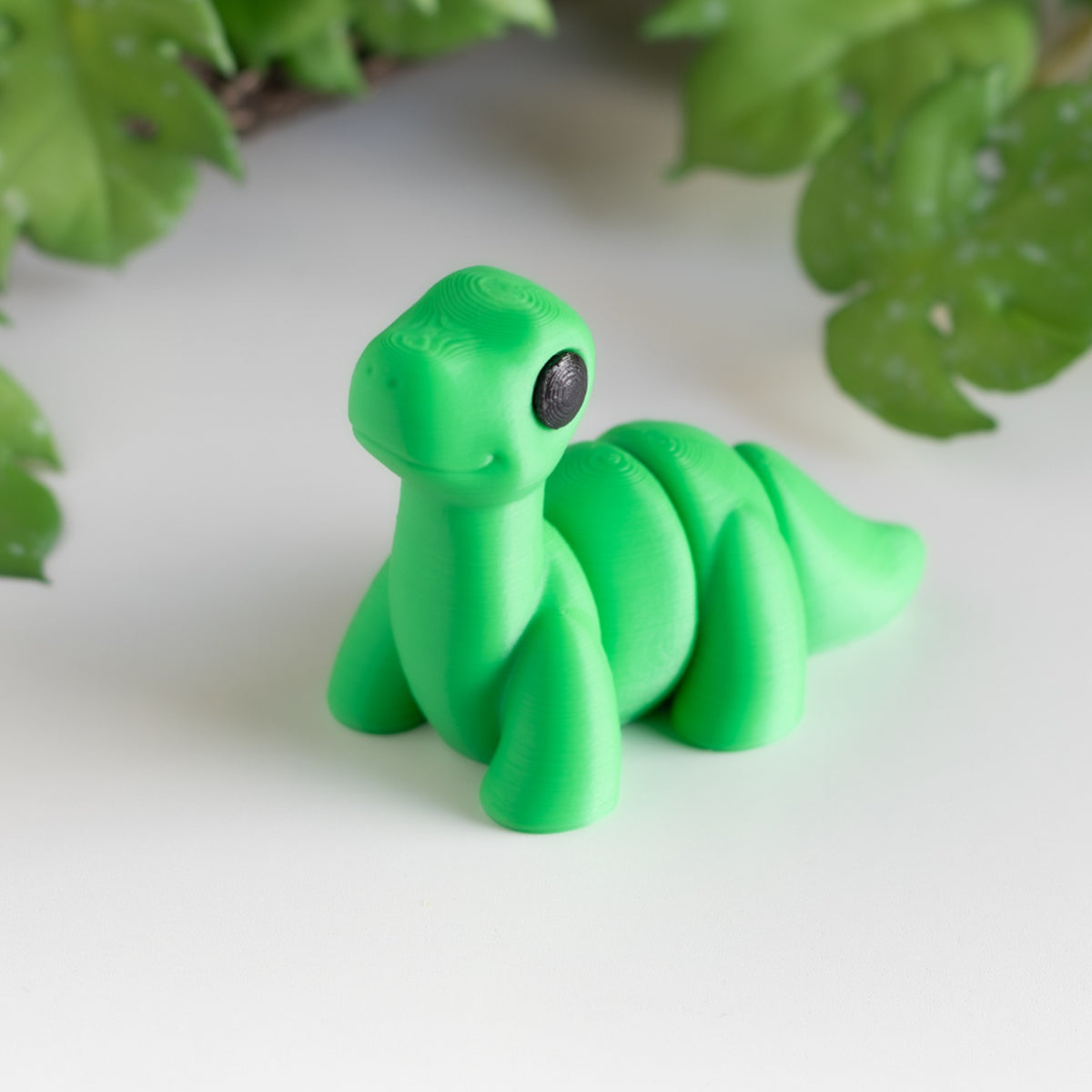 Baby Brontosaurus — 3D printed long-necked dinosaur figurine, shown in green with black eyes